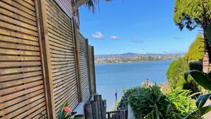 A pathway leading to a waterfront view, flanked by wooden slats and plants. - Unique property overlooking estuary to city on the beautiful Daisy Hardwick walk (Tauranga)