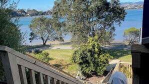 A wooden staircase leading to a deck overlooking a lake with trees and a clear sky. - Unique property overlooking estuary to city on the beautiful Daisy Hardwick walk (Tauranga)