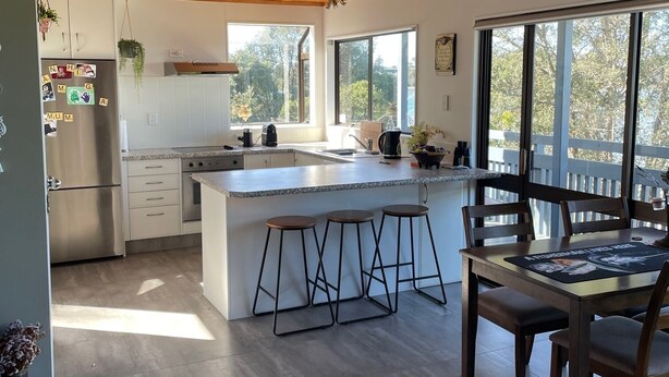 A modern kitchen with a large island, wooden ceiling, and large windows. - Unique property overlooking estuary to city on the beautiful Daisy Hardwick walk (Tauranga)