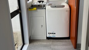 A compact kitchen with a washing machine, a small sink, and a window. - Unique property overlooking estuary to city on the beautiful Daisy Hardwick walk (Tauranga)