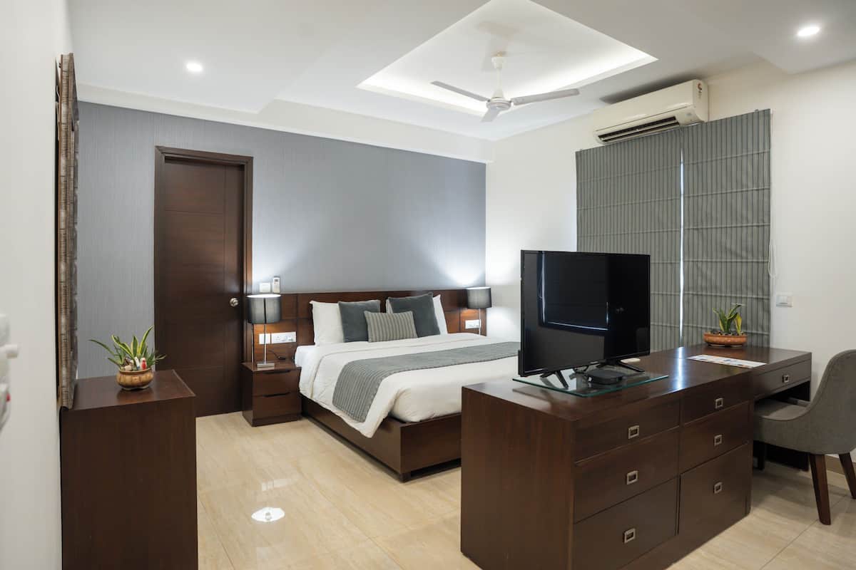Ein modernes Schlafzimmer mit Bett, Schreibtisch, Fernseher und Deckenventilator.