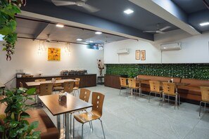 A modern restaurant interior with tables, chairs, a counter, and decorative plants.
