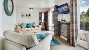Een woonkamer met een bank, een televisie en een open haard.