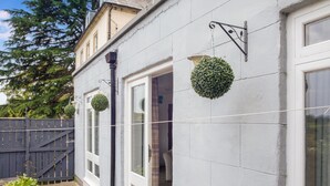 Een gebouw met een witte gevel, een houten hek en een hangende bolvormige plant.