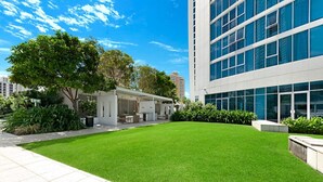 A modern building with a large glass facade, a well-maintained lawn, and a patio area with outdoor furniture.
