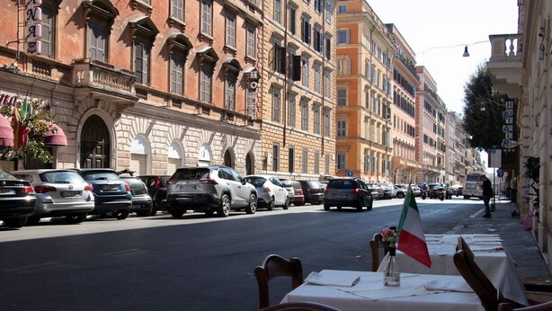 A street with parked cars and a row of tables with flags, suggesting a dining area. - The Best Rent - Apartment close to Termini Station (Roma)