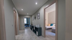 A modern hallway with a wooden floor, a seating area with a table and chairs, and a bed in the adjacent room. - The Best Rent - Apartment close to Termini Station (Roma)