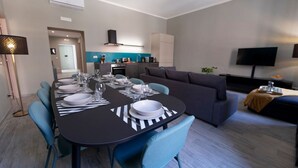 A modern living room with a dining area, a sofa, a TV, and a kitchen in the background. - The Best Rent - Apartment close to Termini Station (Roma)