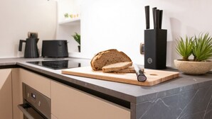 A kitchen with a marble countertop, a cutting board with bread, a knife, a black knife block, and a potted plant. - The Best Rent - Deluxe Piazza di Spagna Apartment (Roma)