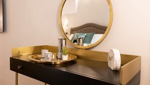 A modern bathroom vanity with a gold-framed mirror, a black countertop, and a tray with a clock and a potted plant. - The Best Rent - Deluxe Piazza di Spagna Apartment (Roma)
