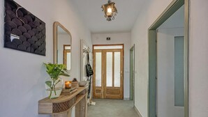 A hallway with a wooden console table, a mirror, a potted plant, and a door with frosted glass panels.