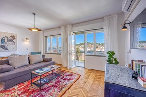 Una sala de estar moderna con un sofá, una mesa de centro y vistas de la ciudad a través de amplios ventanales.