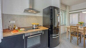 A modern kitchen with a black refrigerator, wooden countertop, and a dining area with a table and chairs.