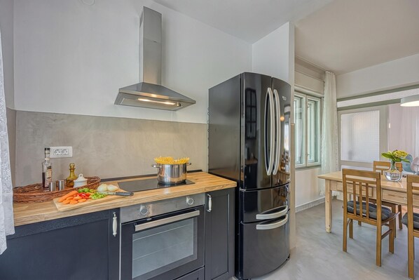 Une cuisine moderne avec un réfrigérateur noir, un plan de travail en bois et un coin repas comprenant une table et des chaises.