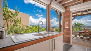 A kitchen with a large window, a sink, and a dining area with a table and chairs.