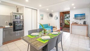 Een moderne keuken met inbouwapparatuur, een eethoek met een tafel voor vier personen en uitzicht op de omgeving via een open deur.