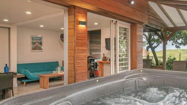 Een bubbelbadgedeelte met een houten plafond, een smaragdgroene bank en een kleine tafel.