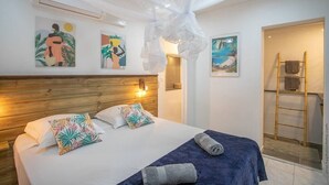 Een hotelkamer met een bed, een houten hoofdeinde, een klamboe en kunst aan de muur.