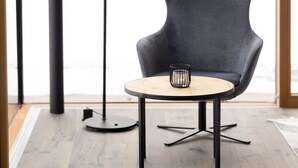 A modern room with a round table, a dark armchair, and a floor lamp. - Stadler Hof - Orangery (Lana)