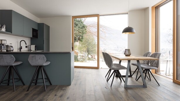 A modern kitchen with a bar area, dining table, and chairs. - Stadler Hof - Orangery (Lana)