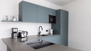 A modern kitchen with grey countertops, a built-in sink, a microwave, and a coffee maker. - Stadler Hof - Orangery (Lana)