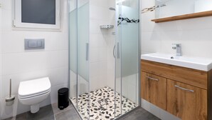 Een moderne badkamer met een douchecabine van glas, een toilet, een wastafel en houten kastjes.