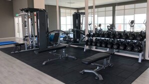 A gym with weight machines, dumbbells, and a bench.