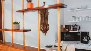 A kitchen with a microwave, coffee maker, and shelves with dishes and jars. - Escape to this artsy 2-bedroom MCM Guesthouse in charming Phoenix, OR. Unwind in the luxurious spa soaking tub after exploring Southern Oregon. Features high-end design for a stylish, quiet retreat. (Phoenix)