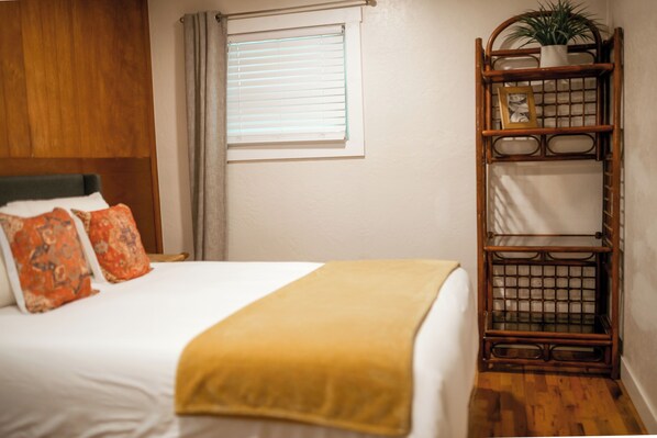 A neatly made bed with a yellow throw, a wooden headboard, and two patterned pillows.