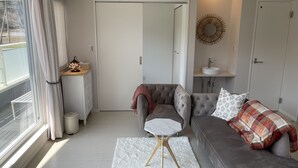 A modern living room with a grey sofa, a white rug, and a small side table. - Mt. Fuji koko wantyanOK sintikubessō (Fujikawaguchiko)