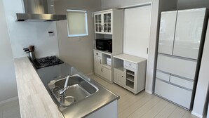 A modern kitchen with a stainless steel sink, a gas stove, white cabinetry, and a built-in microwave. - Mt. Fuji koko wantyanOK sintikubessō (Fujikawaguchiko)