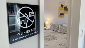 A sign prohibiting pets in the bedroom, a bed with floral bedding, and a nightstand with a lamp. - Mt. Fuji koko wantyanOK sintikubessō (Fujikawaguchiko)