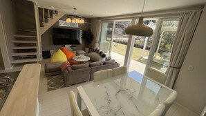 A modern living room with a sofa, a dining table, and a TV. - Mt. Fuji koko wantyanOK sintikubessō (Fujikawaguchiko)