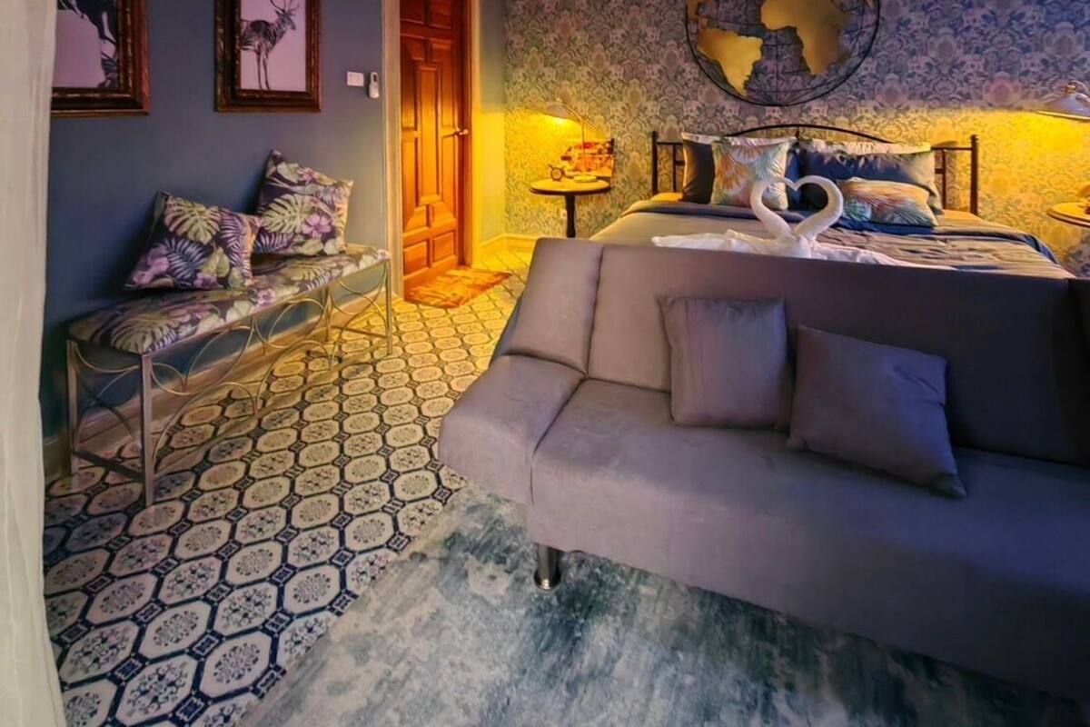 A cozy living room with a patterned floor, a sofa, a bench, and a globe on the wall.