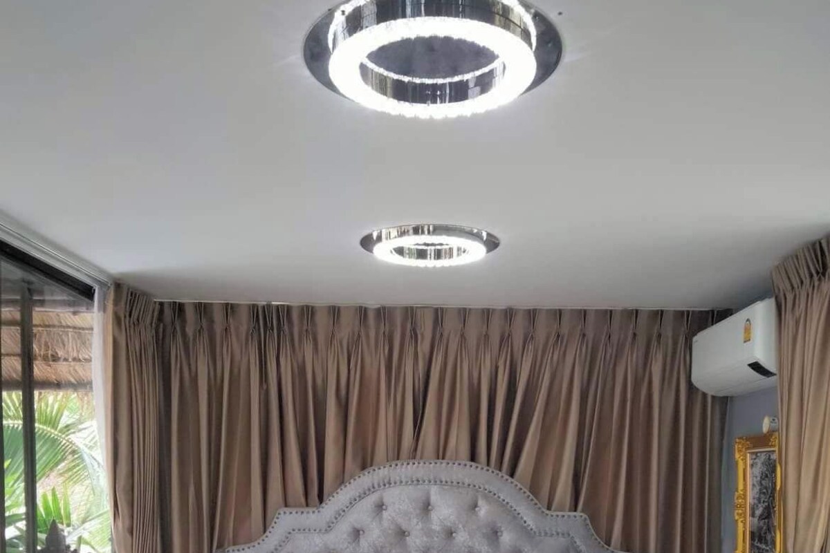 Ein Schlafzimmer mit einer gepolsterten Kopfteil, einem Bett mit einem gemusterten Bettdecken und einer herzförmig drapierten Handtuchanordnung.