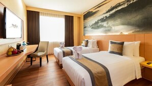 A hotel room with two beds, a desk, a chair, and a large painting on the wall. - Horison Diana Timika (Timika)