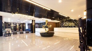 A modern hotel lobby with a reception desk, seating area, and a decorative sculpture. - Horison Diana Timika (Timika)