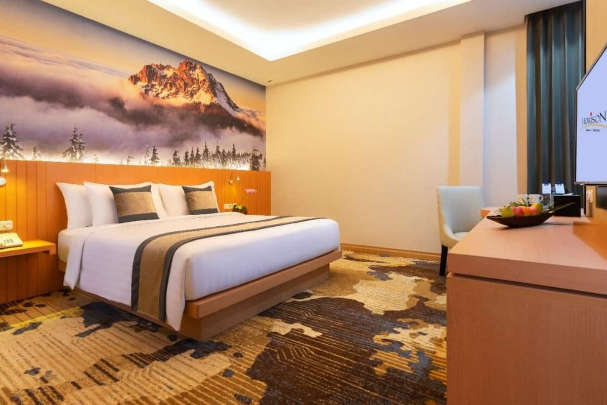 Een hotelkamer met een bed, een bureau, een televisie en een wanddecoratie.