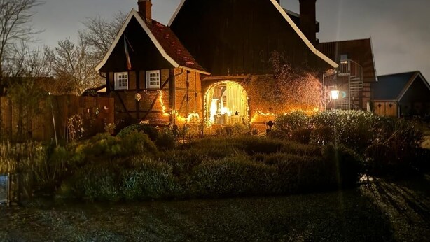 Ein traditionelles Holzhaus mit einer großen Veranda und einem Rundfenster, umgeben von einem gepflegten Garten.