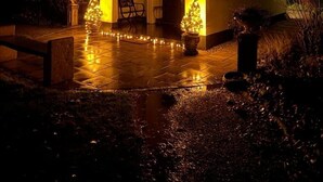 Ein Haus mit einem gefliesten Vorbau, einer hölzernen Bank und einem kleinen Weihnachtsbaum.