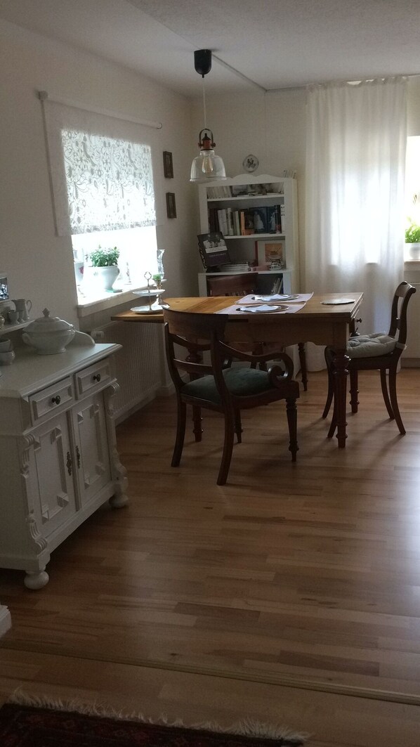 A dining area with a wooden table and chairs, a white cabinet, and a bookshelf. - The Emtingshof is located in the middle of a dream garden. (Selm-Cappenberg)