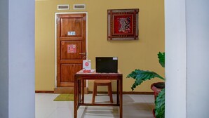 Una puerta de madera con un letrero, una obra de arte enmarcada en la pared, un ordenador portátil sobre una mesa y una planta en maceta.