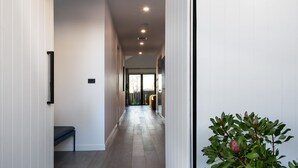 A hallway with a bench, a plant, and a door leading to a room.