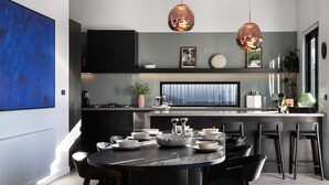 A modern kitchen with a central island, black cabinets, and copper pendant lights.