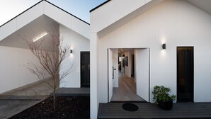 A modern building with a minimalist design, featuring a wooden deck and a potted plant.