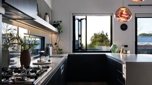 A modern kitchen with a gas stove, a large window, and a view of the outdoors.