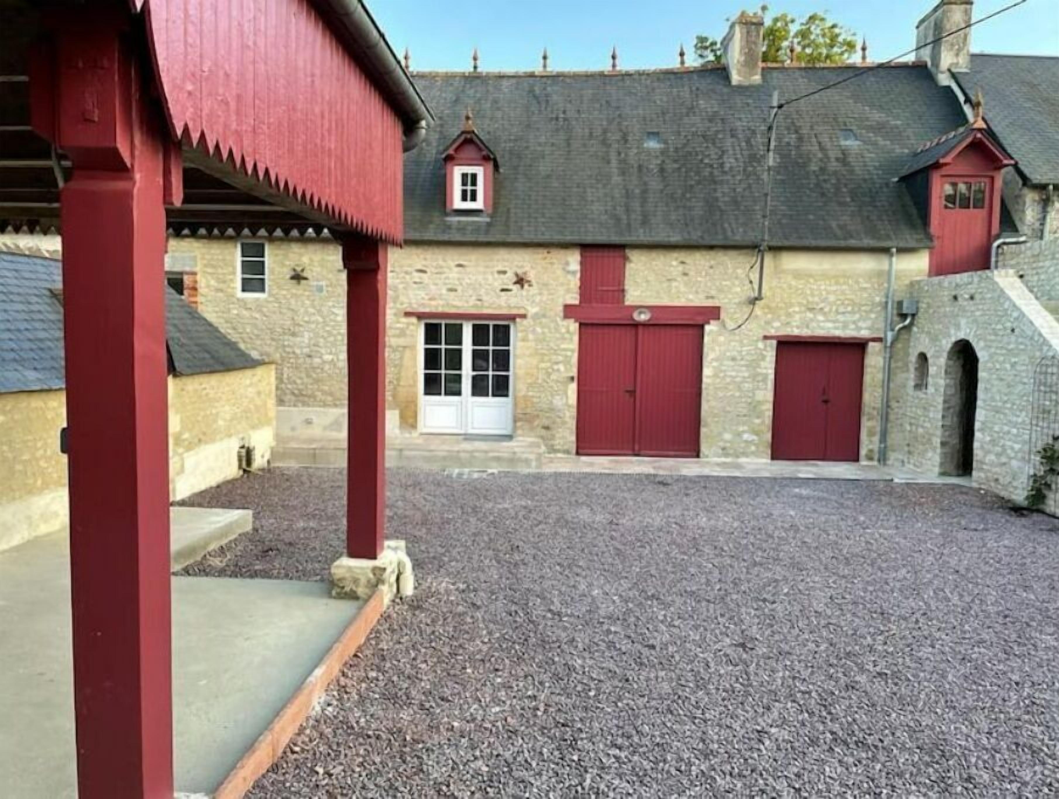 A building with a gravel courtyard, red doors, and stone walls.