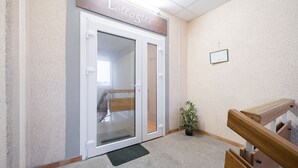 A hotel entrance with a sign reading "Lollostee," a wooden bench, a small potted plant, and a tiled floor. - Lollo Motel Graičiūno - Lollo Luxury (Vilnius)