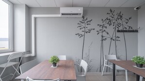 A modern meeting room with a brown table, white chairs, and potted plants. - Lollo Motel Graičiūno - Lollo Luxury (Vilnius)