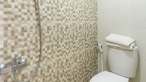A bathroom with a tiled mosaic wall, a toilet, and a shower with a hose. - OYO Life 3782 Gunung Anyar (Surabaya)